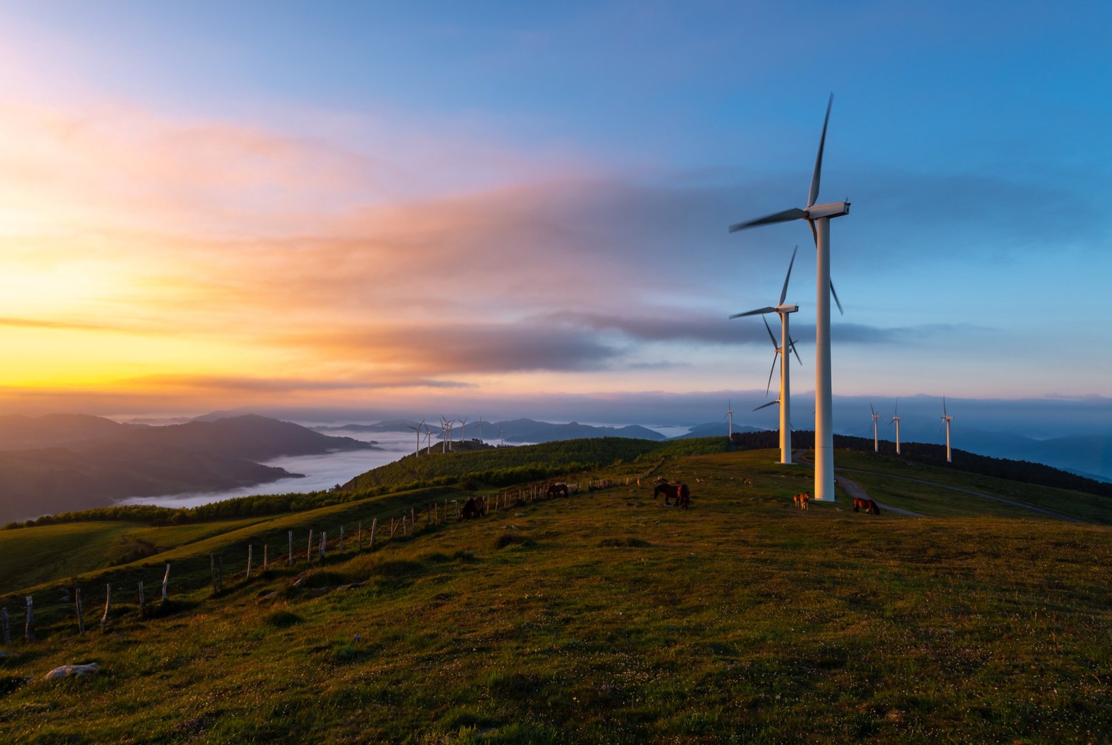 Solar panels and wind turbines against green mountains